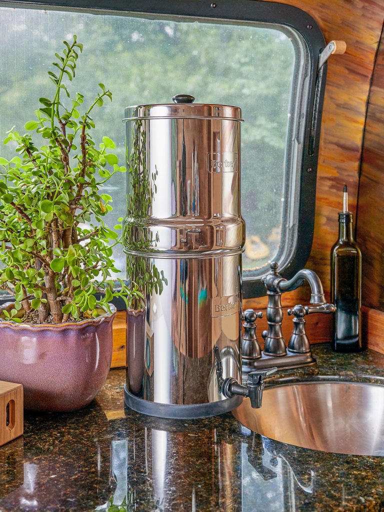 Berkey waterfilter, op aanrecht in camper voor raam, plant, wasbak