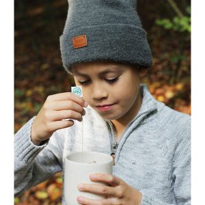 Un niño prepara una taza de té en otoño