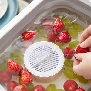 pesticide cleaner in container of water with tomatoes, strawberries and grapes