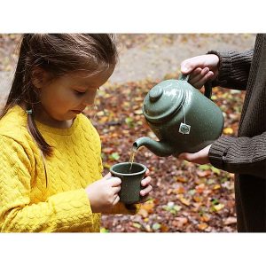 Pouring tea for girl, green mug and tea pot