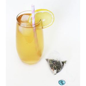 Thé froid Lemon Lagoon dans un verre avec glaçons et rondelle de citron, paille, sachet de thé Okae for Kids