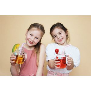 Dos niñas con vaso de té infantil frío con fruta, pajita