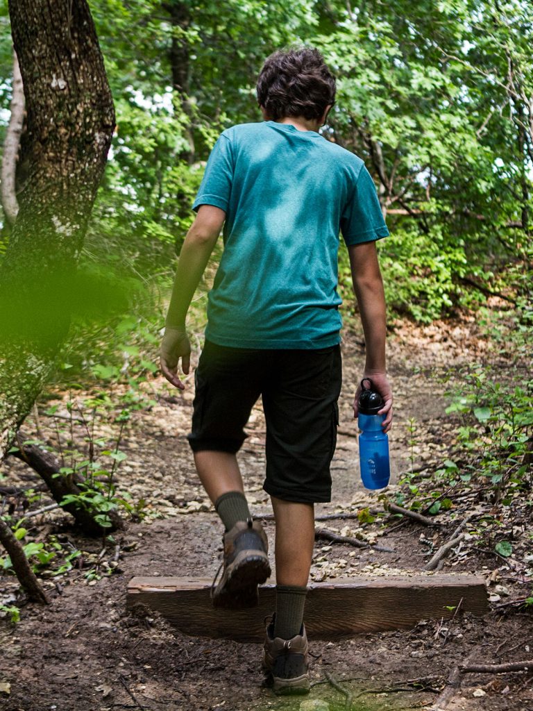 Wanderer mit Sport Berkey Wasserflasche blau auf Wanderweg